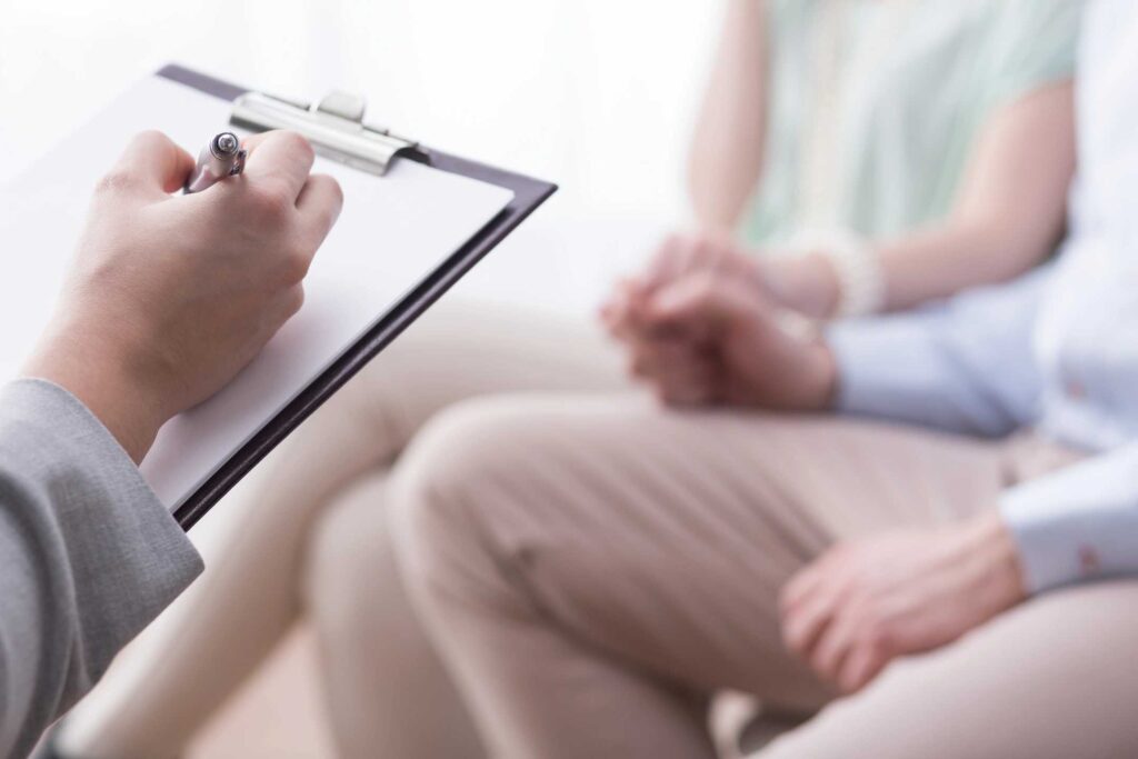 qtq50-GDSVD0 counselor taking notes as couple holds hands during an intensive therapy session.